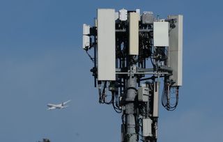 A plane flies by a cellular tower as it takes off from San Francisco International Airport