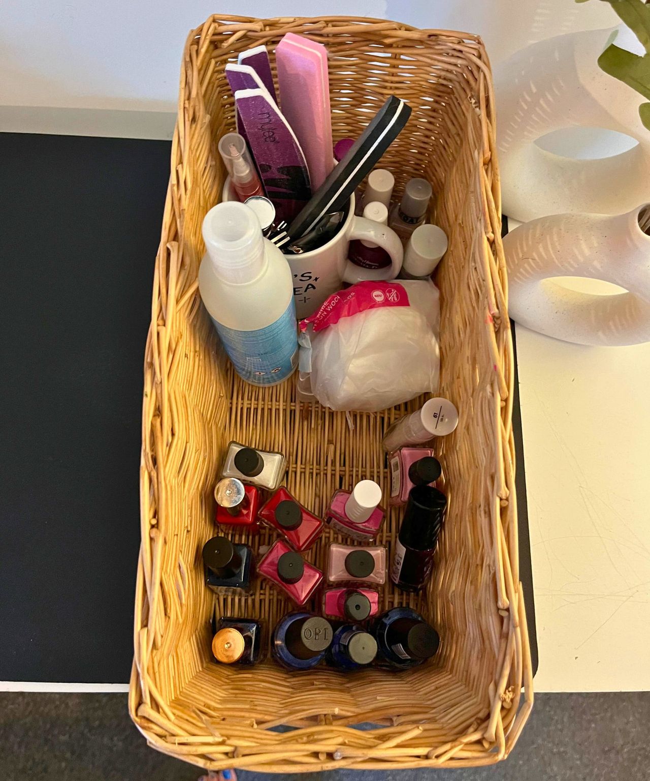 Nail drawer after tidying showing a dozen nail polishes in color order from pink to blue, vertical acetone bottle, a cup with nail files and lots of clear space