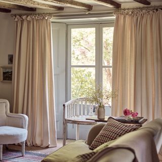 Neutral curtains at a country cottage window with beamed ceilins