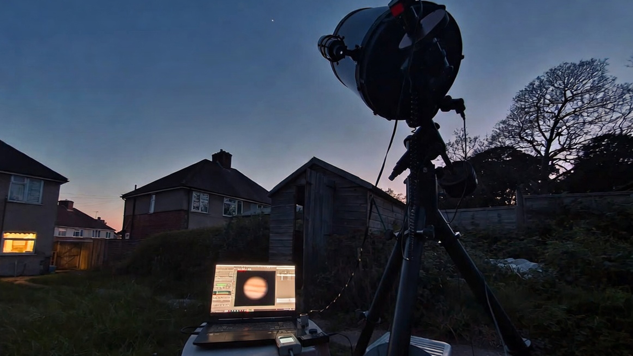 A telescope and laptop setup in a garden, with a dedicated camera attached to the telescope. 