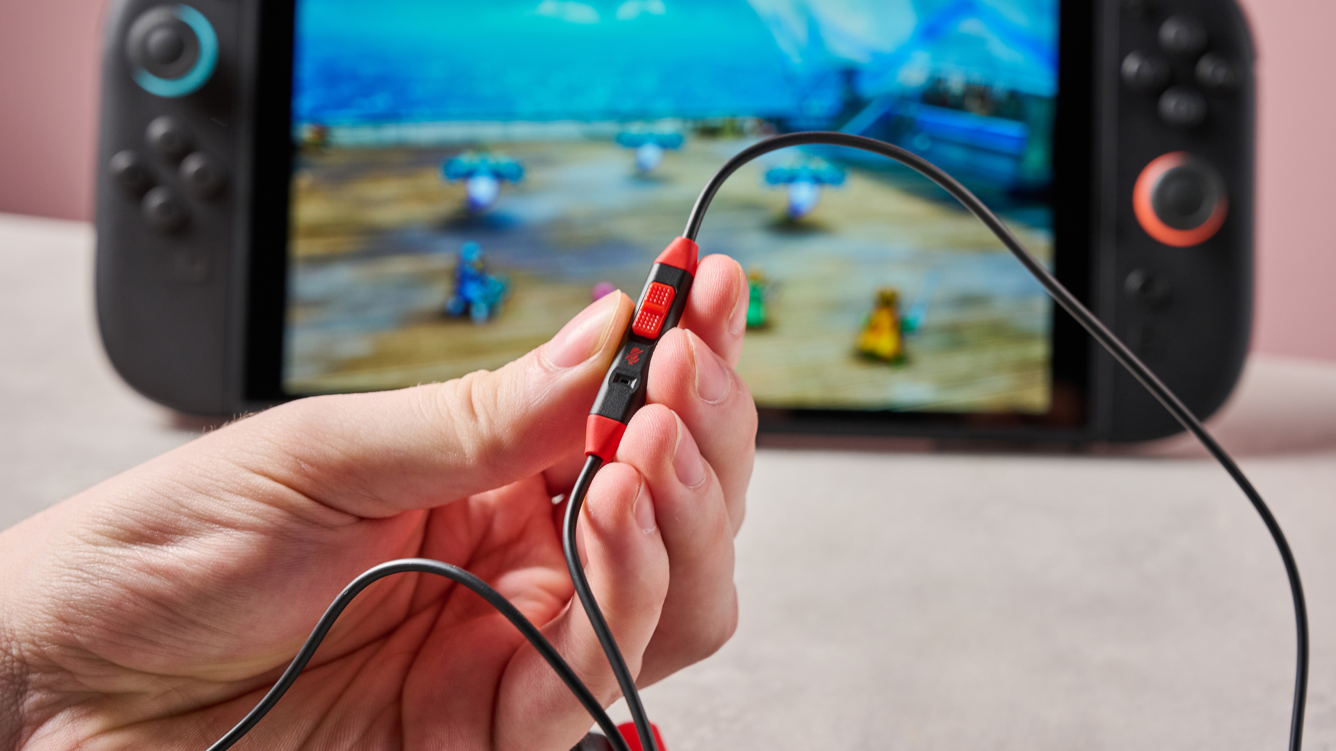 Person holding PowerA Wired Earbuds for Nintendo Switch 2 beside Switch 2 console with Dragon Quest I &amp;amp; II HD-2D Remake on display