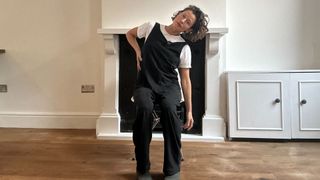Naomi Annand performs side bend yoga move in a chair
