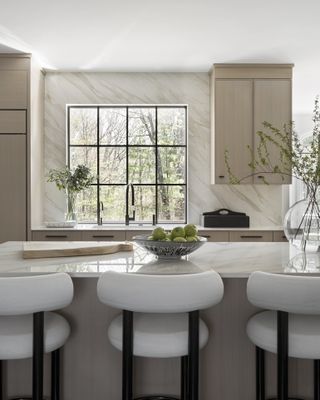 A neutrally decorated modern kitchen with a large island and wing-backed bar stools