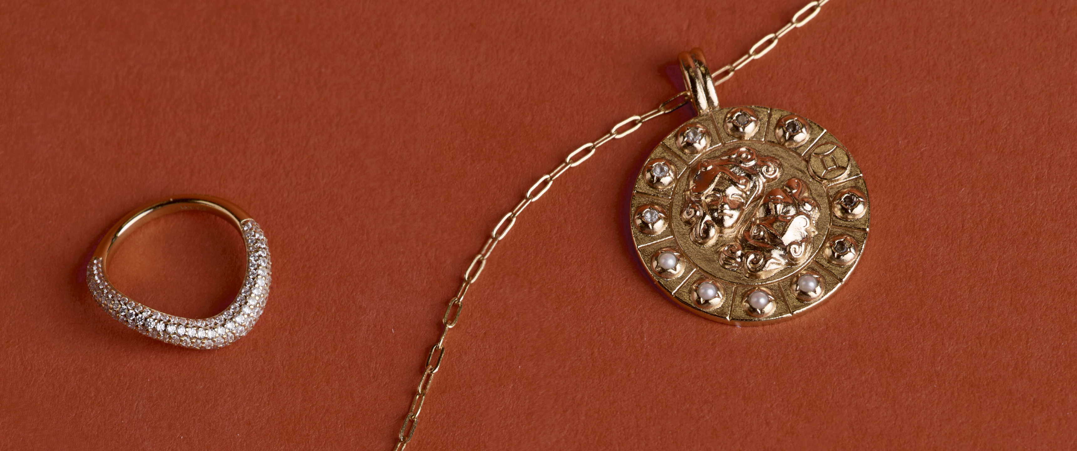 Gold Astrid & Miyu jewellery on a burnt orange background