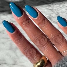 A close-up of a petrol blue manicure
