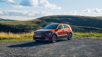 Kia Niro EV parked with green hills in background