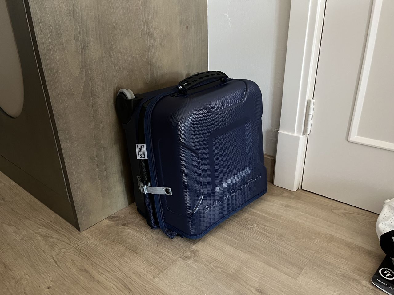 The Sun Mountain travel cover folded away on a hotel roomf loor