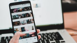 A photo of someone using the Instagram photo app in front of a computer.