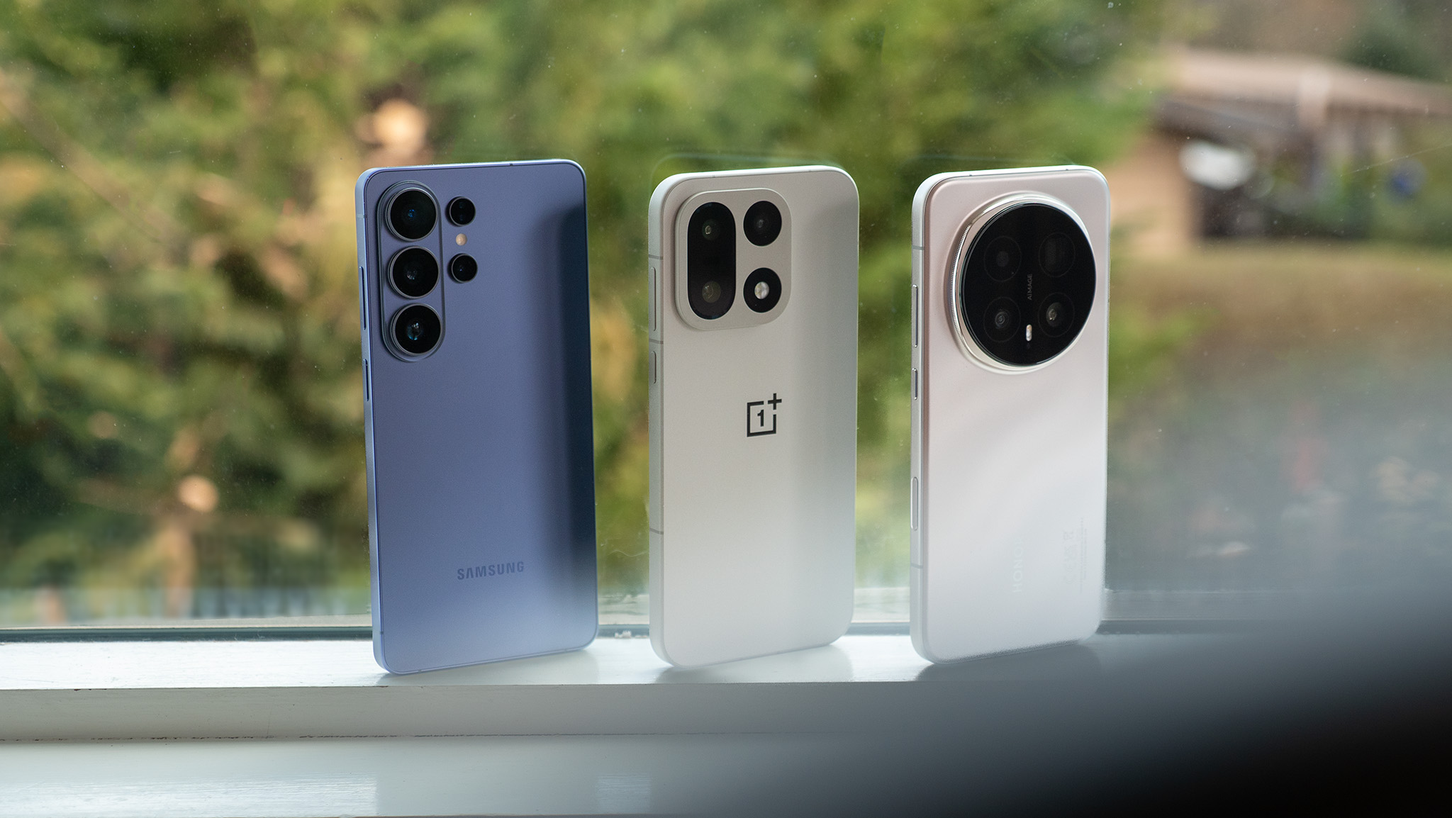 A Samsung Galaxy S26 Ultra, OnePlus 15, and Honor Magic 8 Pro on a windowsill