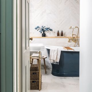 Tiled neutral bathroom with navy bathtub and storage units