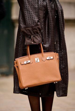 a street-style photo of a woman carrying a Hermés bag in a story about how to buy a hermés bag