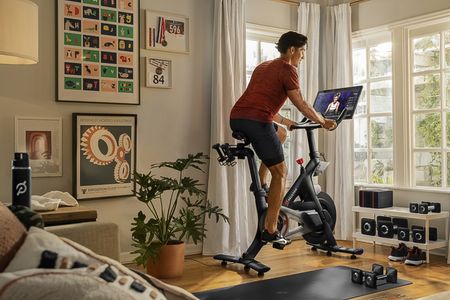 Rider at home on the Peloton bike doing a workout with instructor showing on screen