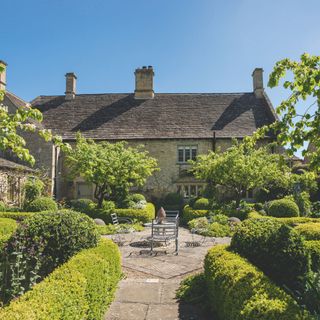 Topiary hedges in garden surrounding concrete garden path and seating area