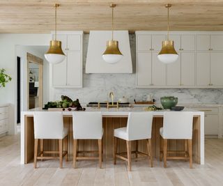 White kitchen with wooden panelling and kitchen island made from wood and calacatta marble