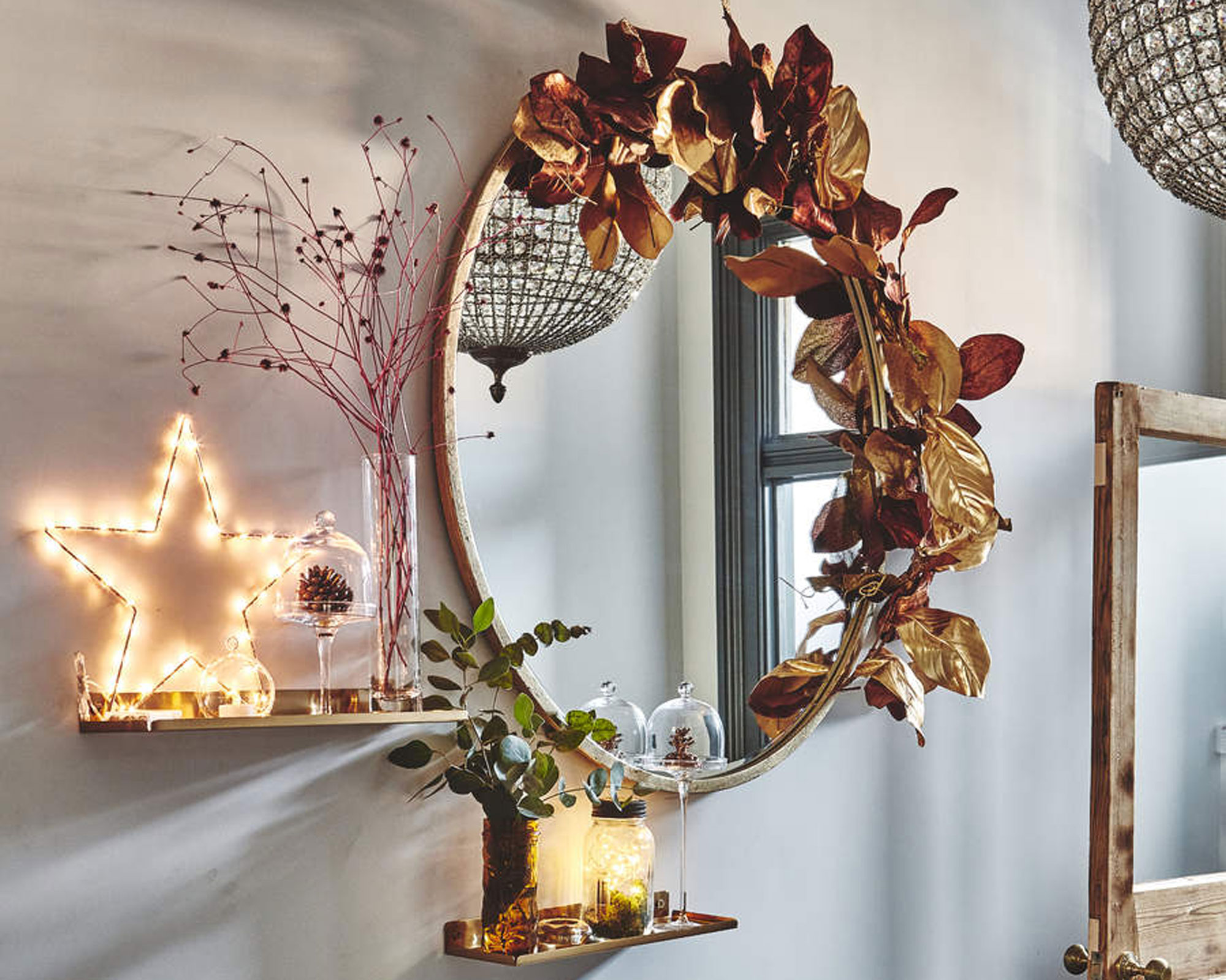 hallway with festive shelfie styling and large round mirror with metallic sprayed foliage