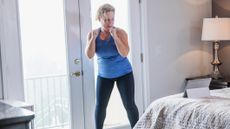 Woman exercising at home looking at a tablet resting on a bed