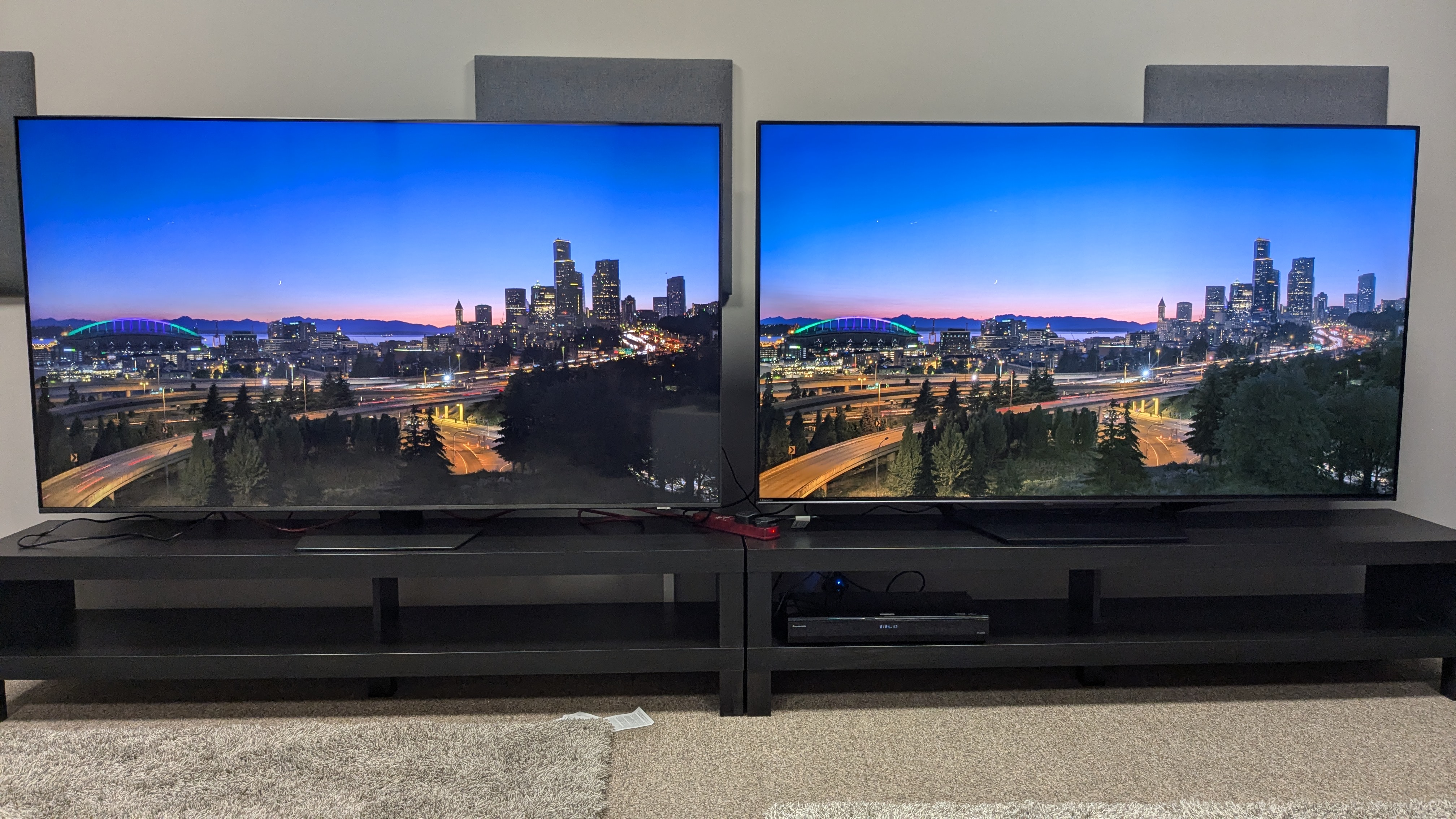 Samsung Qn85D y HIsense U7N con vista de la ciudad al atardecer en pantalla