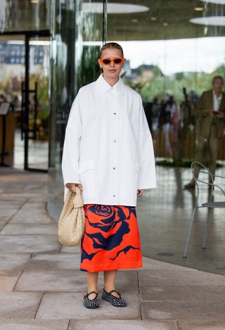 woman wearing oversized button down shirt, skirt, and flats