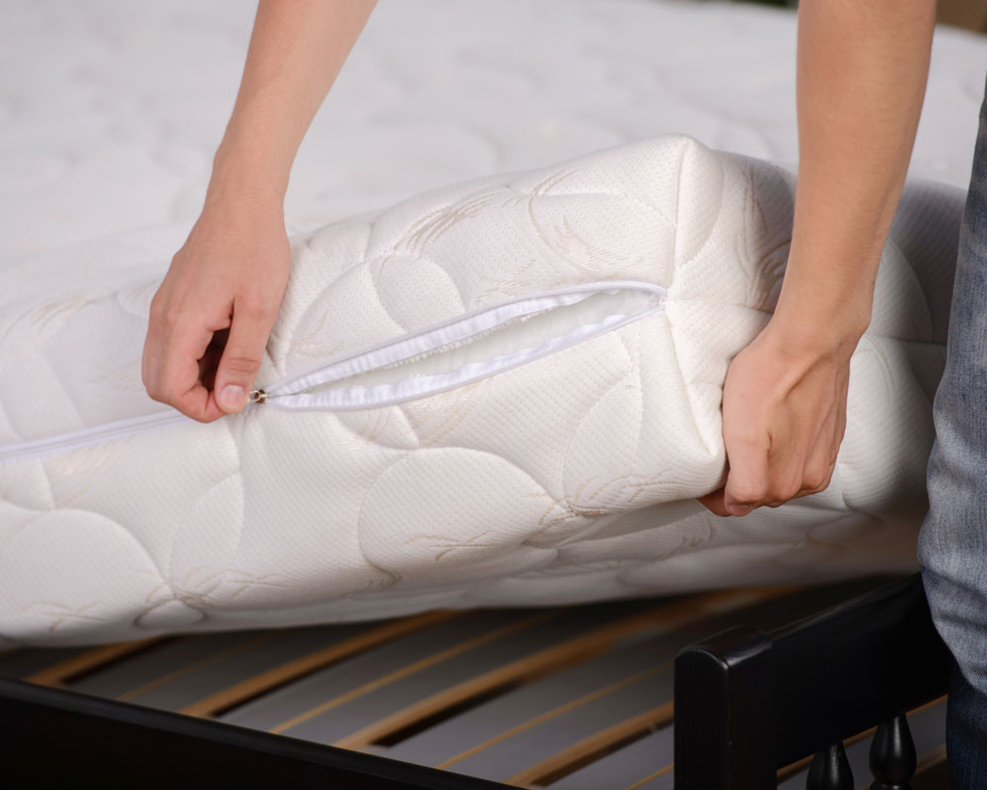 A white quilted mattress being flipped by female wearing denim jeans