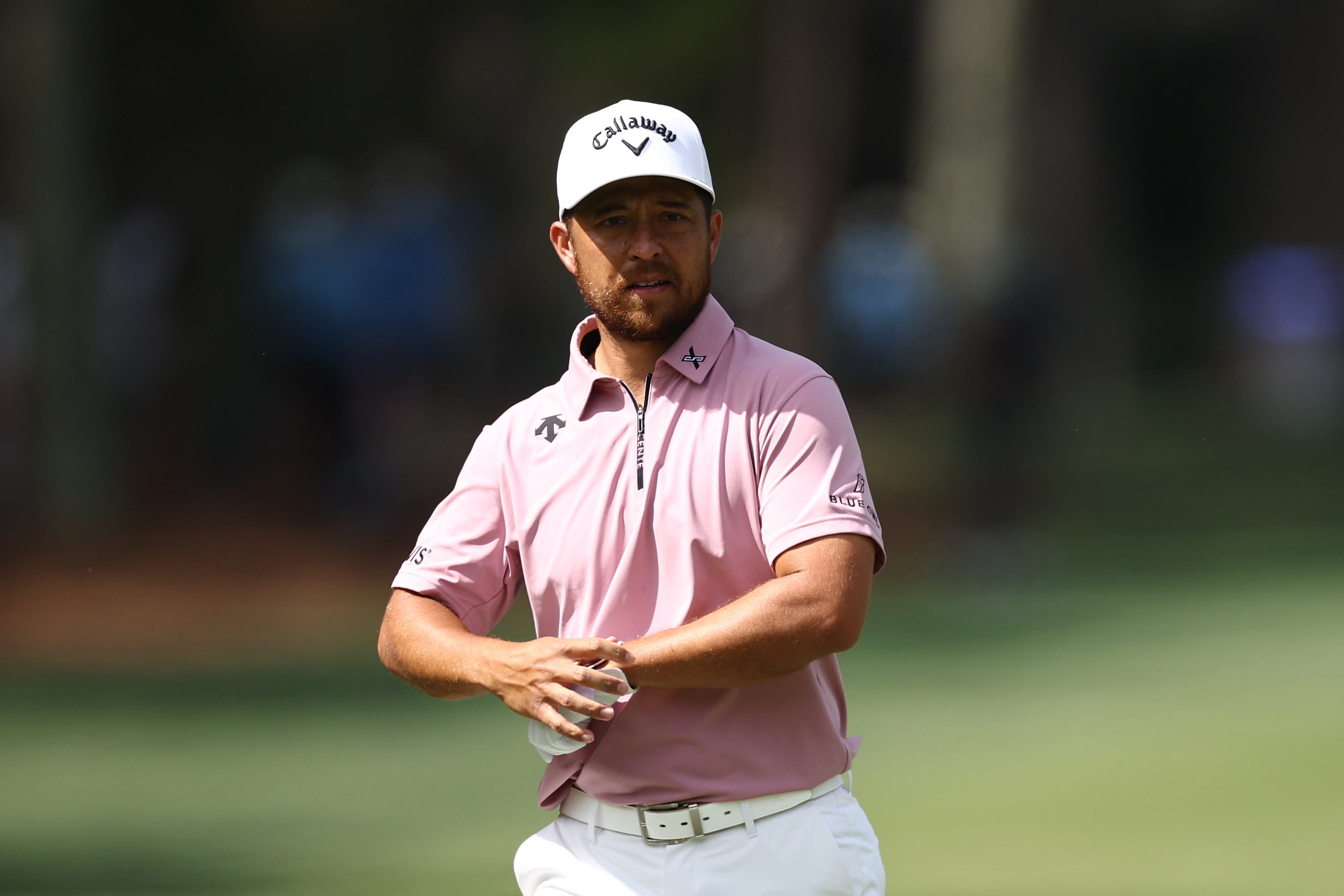 Xander Schauffele puts a glove on walking down the fairway