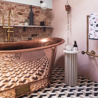 pink bathroom with copper bath and brick wall