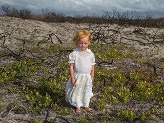 Child in white dress stood in marsh land