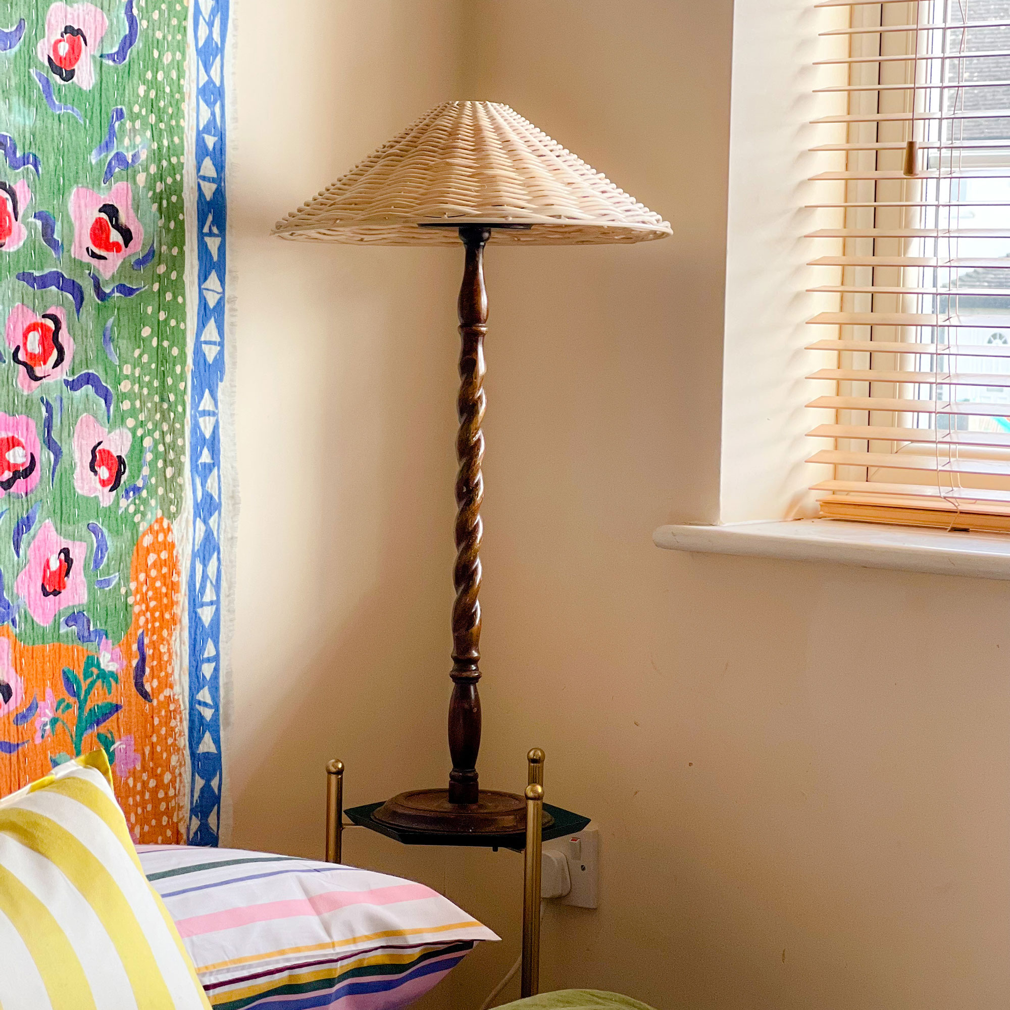 Wooden lamp with raffia shade resting on side table beside bed