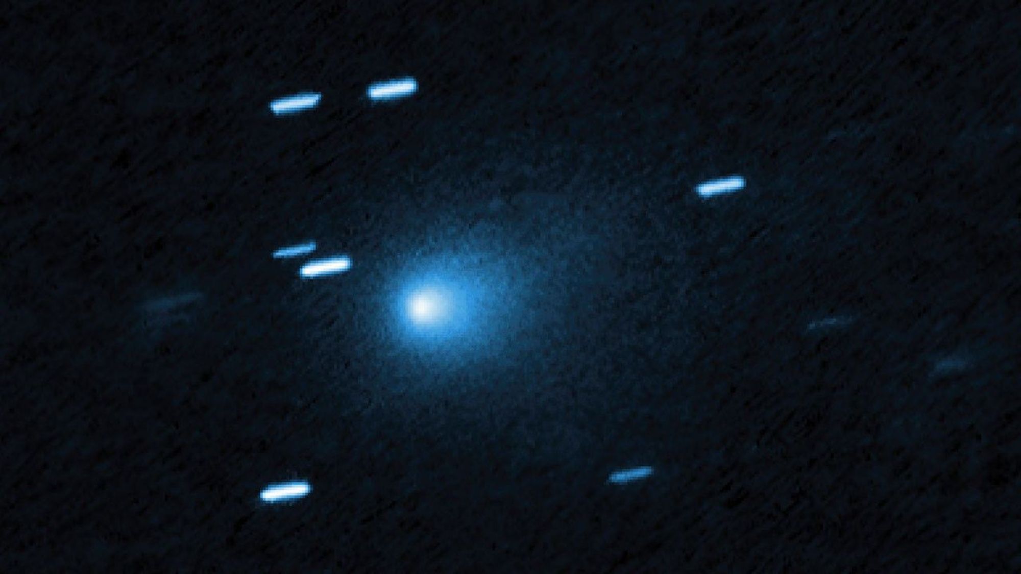 A bunch of blue streaks across a dark background. One blue dot in the middle is hazy.