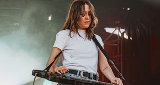 Megal Lovell wears a white T-shirt as she performs outdoors with her lap-steel. For new album Bloom, Megan looked to lap steel luminary David Lindley for inspiration on tones and backline choices.