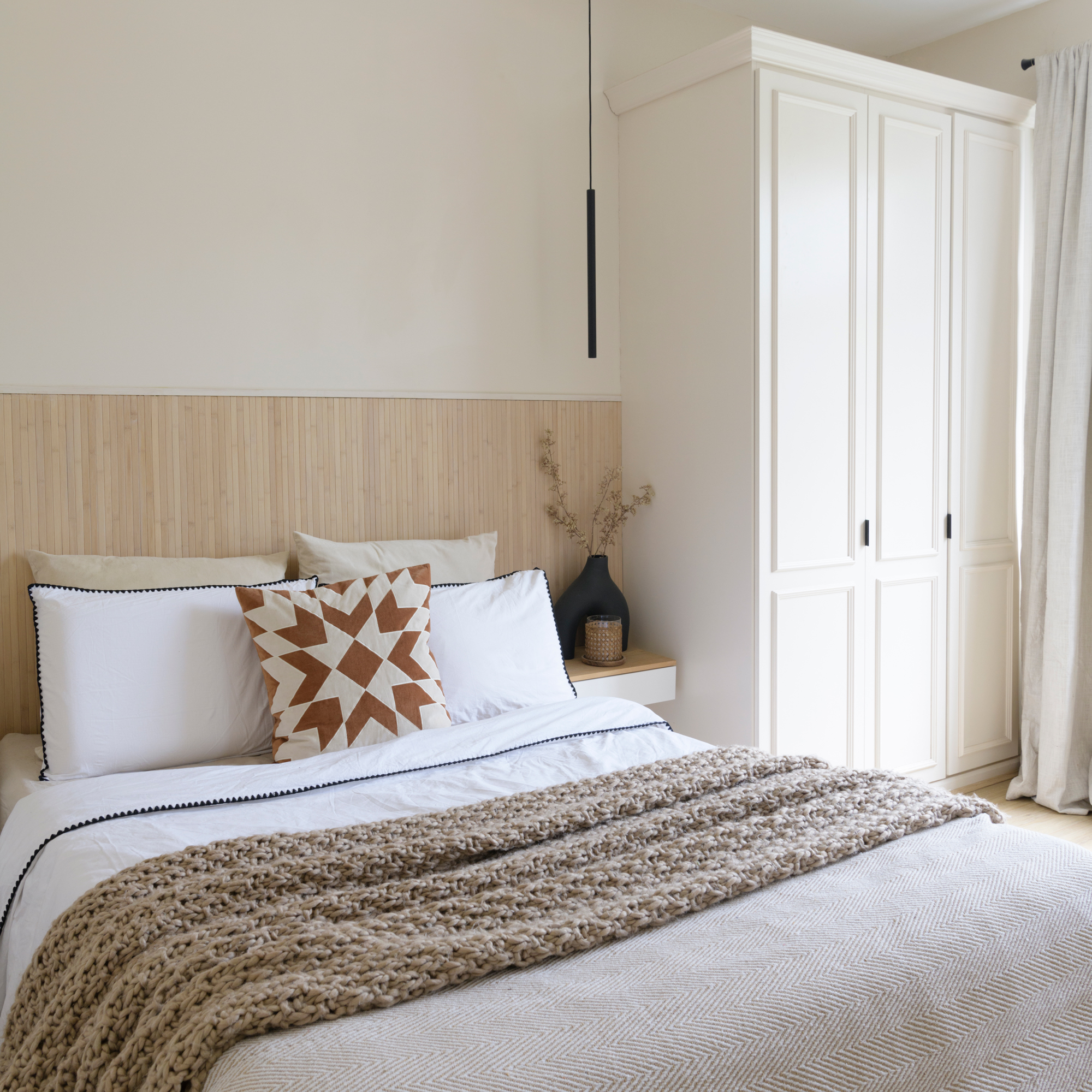 a neutral coloured bedroom with wooden panelling on the walls, and a large storage unit