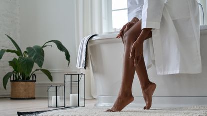woman applying body lotion to her legs