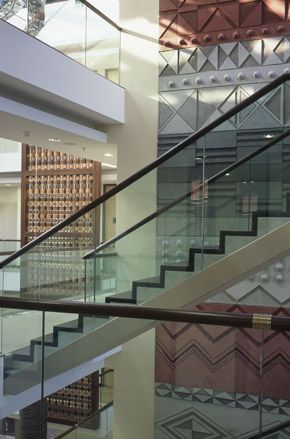 Interior view of the stairwell at the South African Embassy featuring glass balustrades and geometric patterns on the wall in different colours