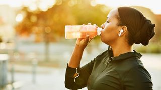 Woman with headphones drinking soft drink from plastic bottle