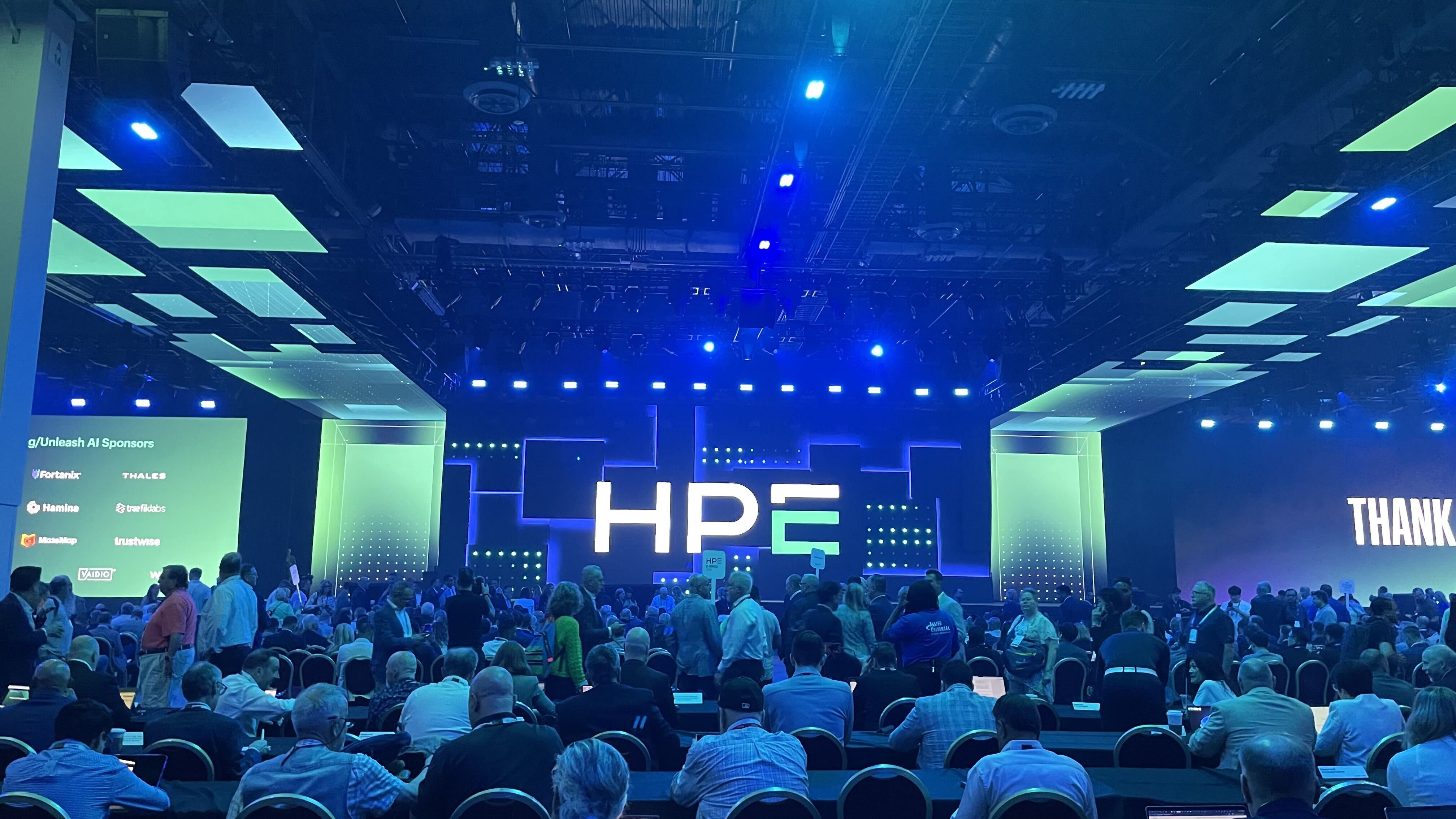The audience at HPE Discover facing the stage, which has HPE in large letters on it.