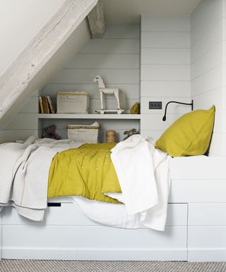 White storage bed and shelves built into an alcove illustrating storage solutions in kids' room ideas.