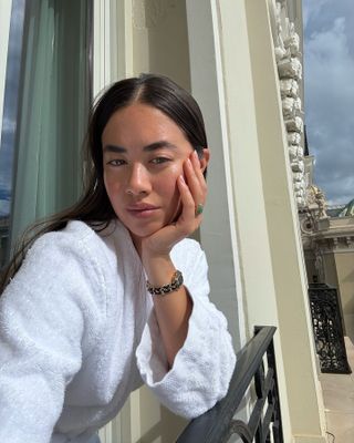 Woman taking selfie on balcony wearing white dressing gown