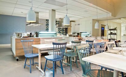 Aveqia kitchen and restaurant with refectory dining tables and white, blue and green wooden chairs