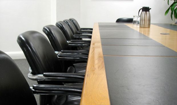 A corporate boardroom filled with empty chairs against a long table