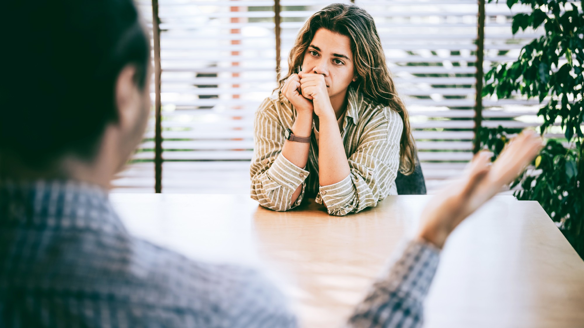 Woman sitting at a desk in the office being scolded by a faceless male boss