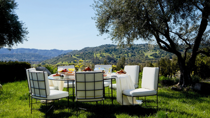 House of Leon wrought iron and boucle dining table and chair set pictured outside on the grass, overlooking the Los Angeles mountains