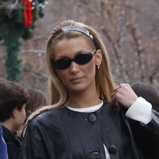 Bella Hadid wearing a black leather jacket, white longsleeve, and white jeans