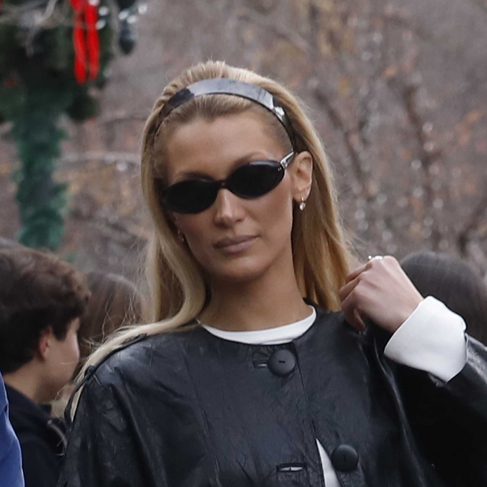 Bella Hadid wearing a black leather jacket, white longsleeve, and white jeans