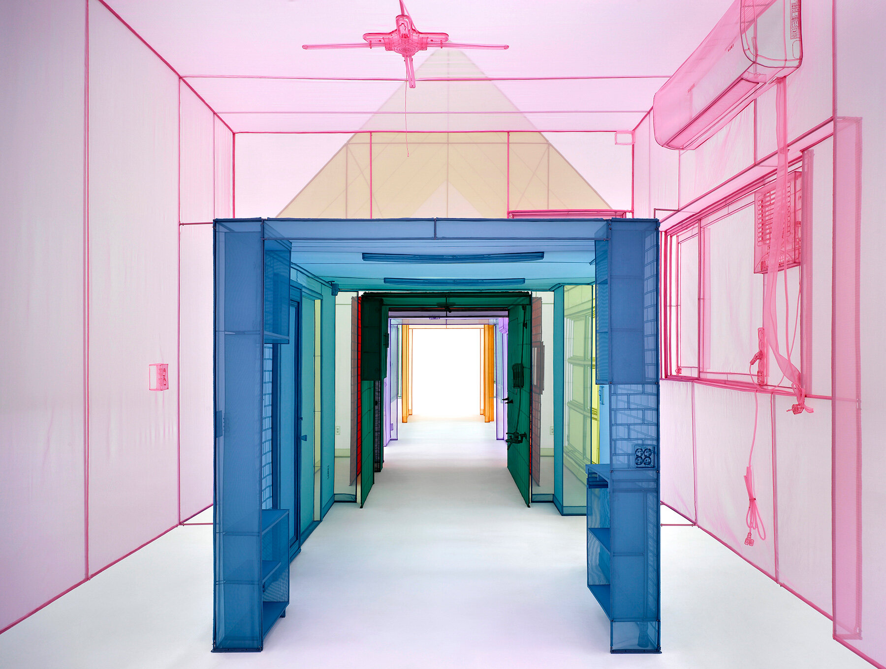 An art installation recreates the feeling of a home through colorful, translucent pieces of fabric woven together.
