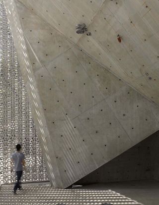 Man walking in a structure with concrete wall and ceiling and metal screen wall