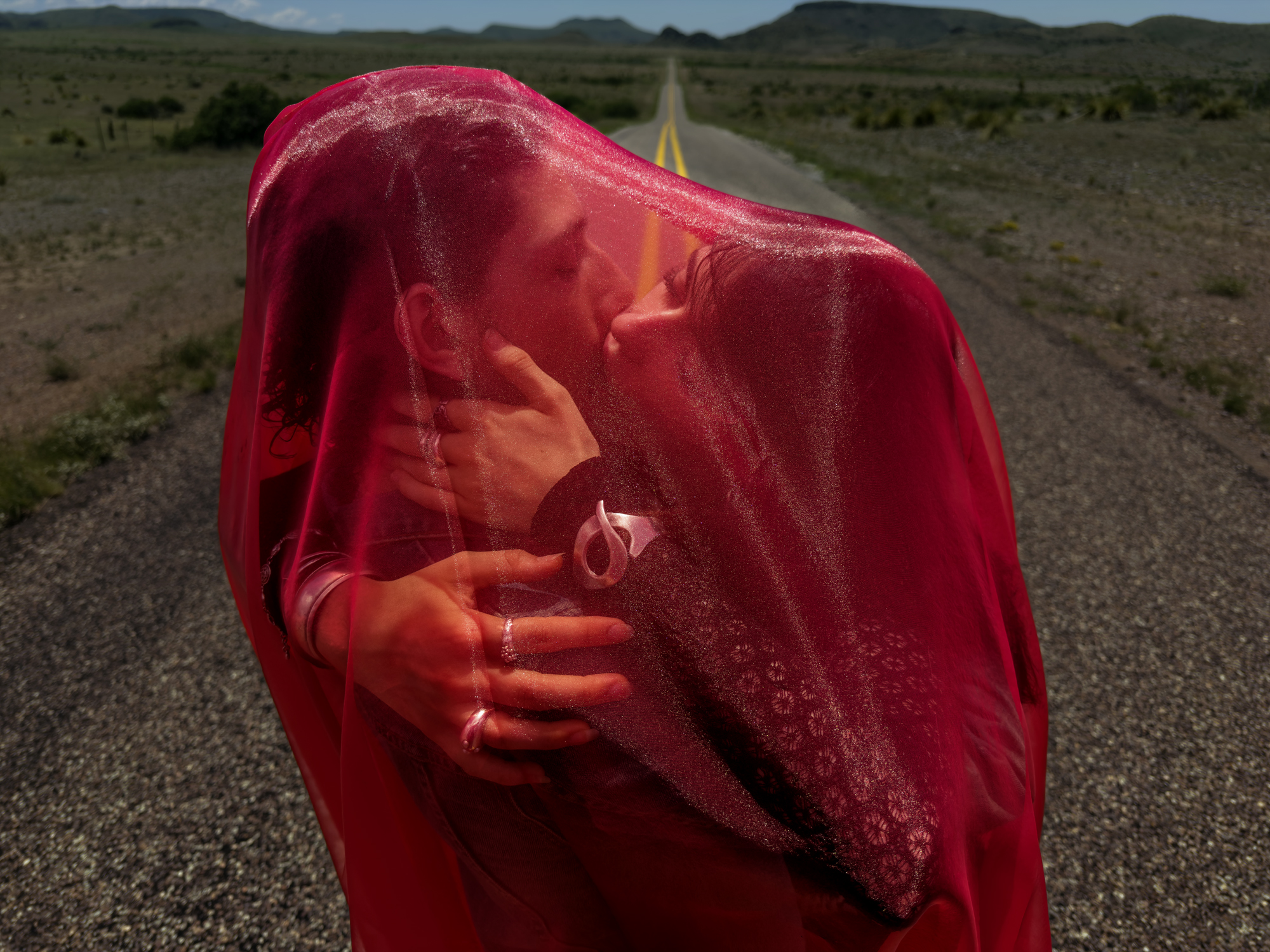 man and woman with red sheet in the desert