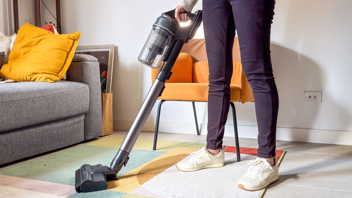 A person holding the Samsung Jet 95S over a carpet
