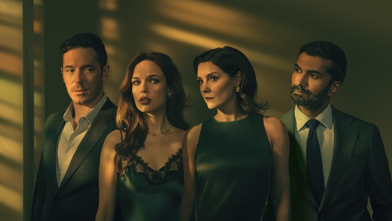 Light through some slats causes alternating shadows to fall across the bodies of four individuals as they stand side-by-side in a dark room. These are (from left to right): Jacob (played by Sam Palladio), Mia (Aggy K Adams), Charlotte (Annabel Scholey) and Leo (Sendhil Ramamurthy) in The Couple Next Door Season 2.
