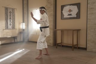 ralph macchio as Daniel LaRusso wearing a karate uniform training in a studio in cobra kai season 6