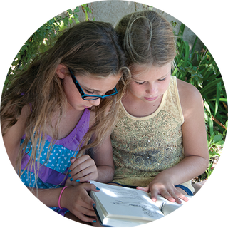 Two young girls reading a book together