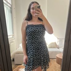 An image of Who What Wear UK fashion writer, Ava Gilchrist, wearing the viral M&S polka-dot lace-trim slip dress. She is a size M and wears it in a size 10. 